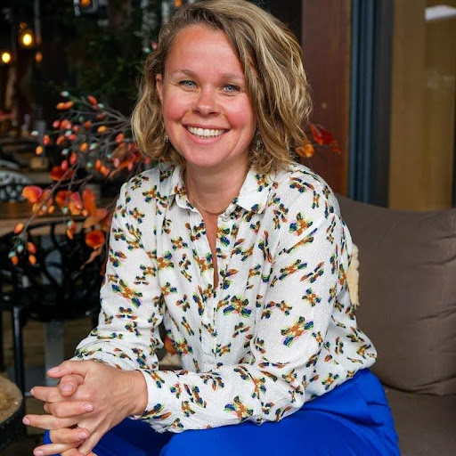 Vrouw glimlacht zittend in herfstdecor.