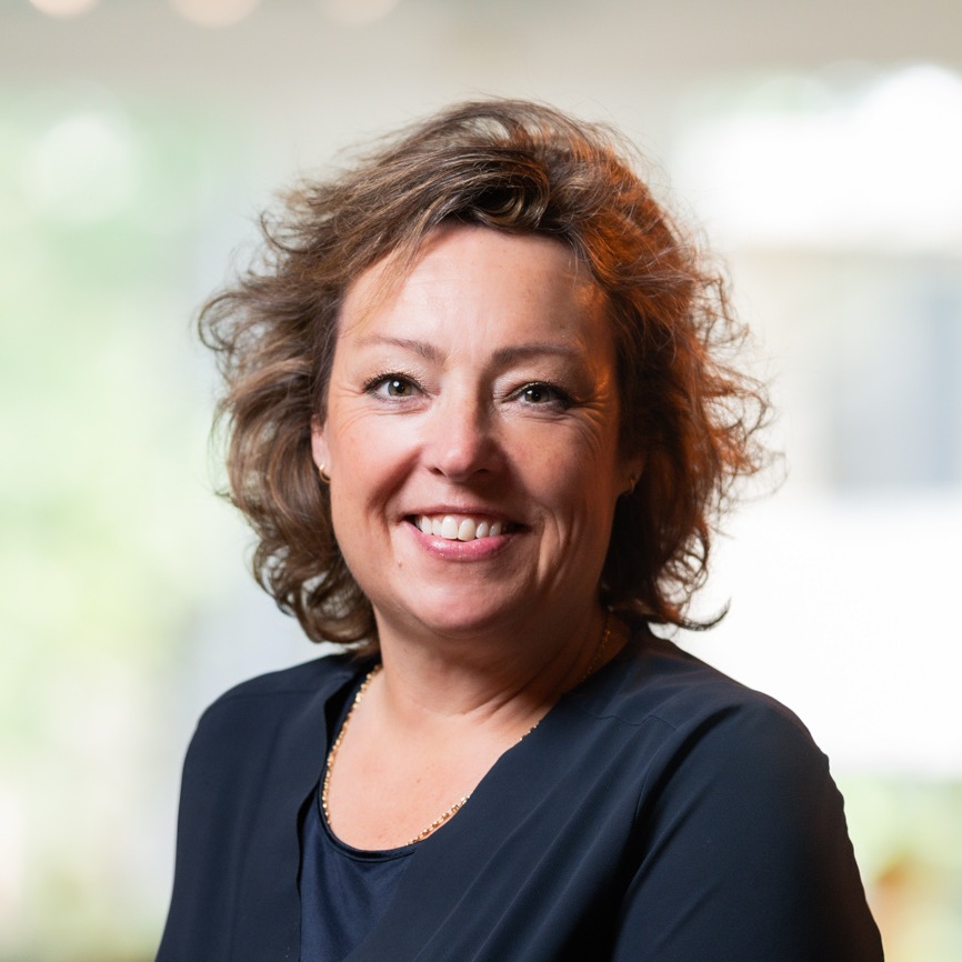 Smiling woman with curly hair in office setting.