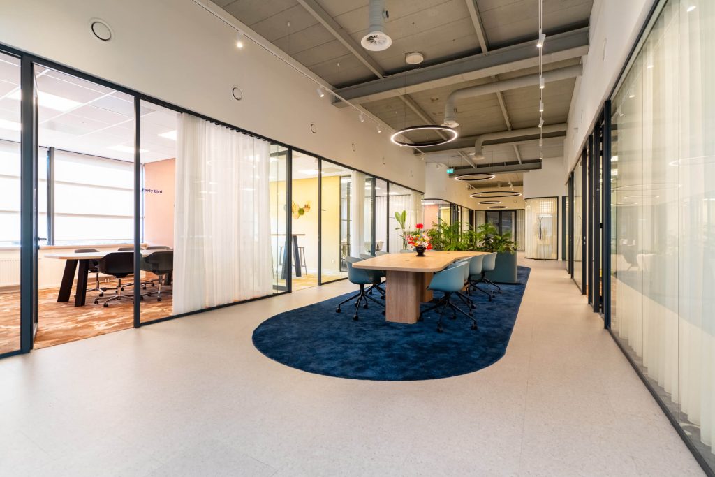 Modern office space with glass walls and meeting table.