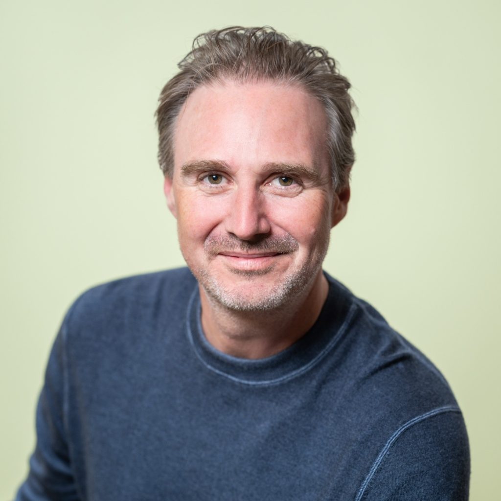 Portret van lachende man in blauwe trui.